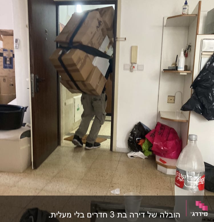 אדם נושא קופסאות גדולות דרך דלת פתוחה